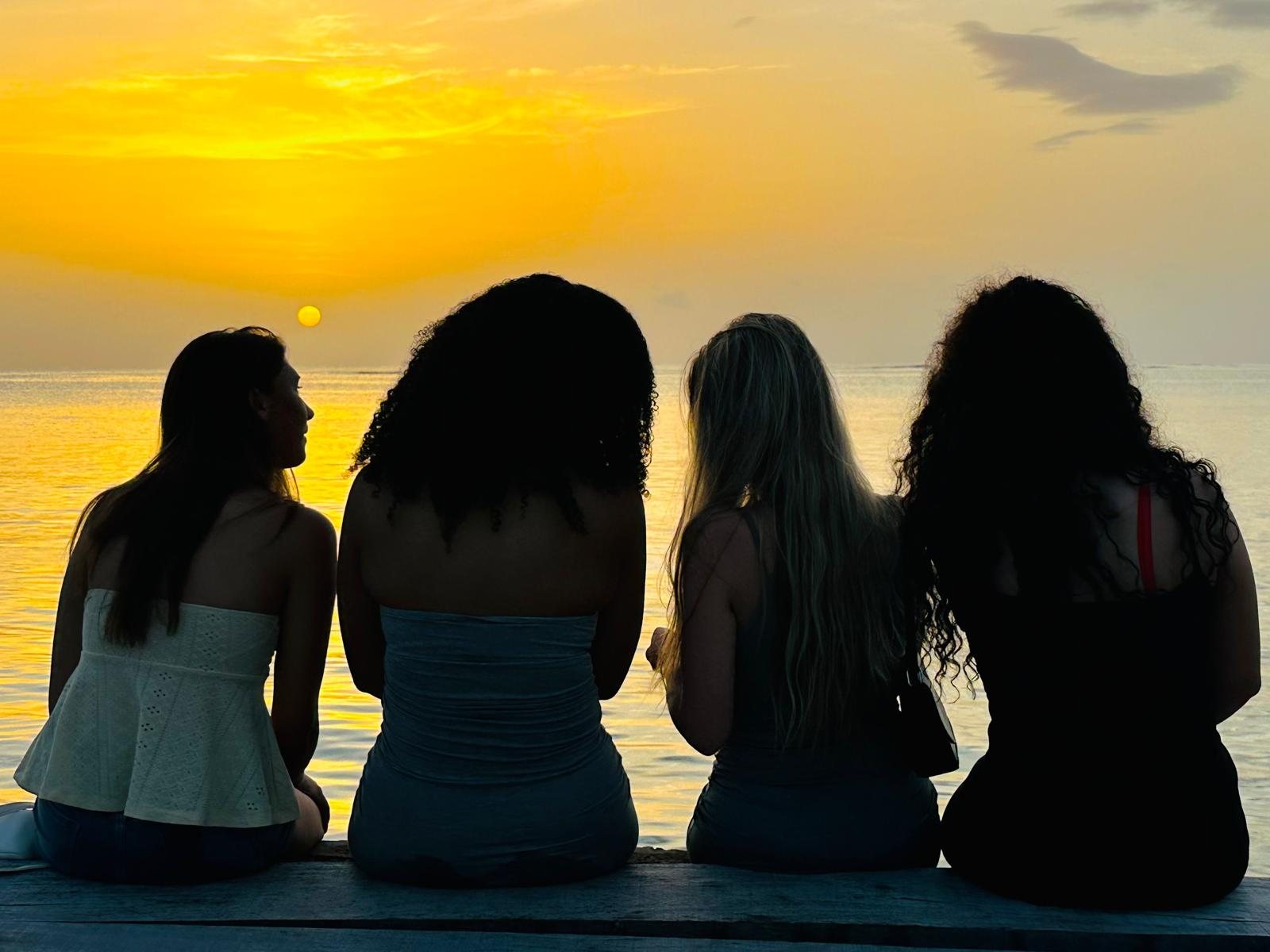 Four girls watching the sunset over the sea