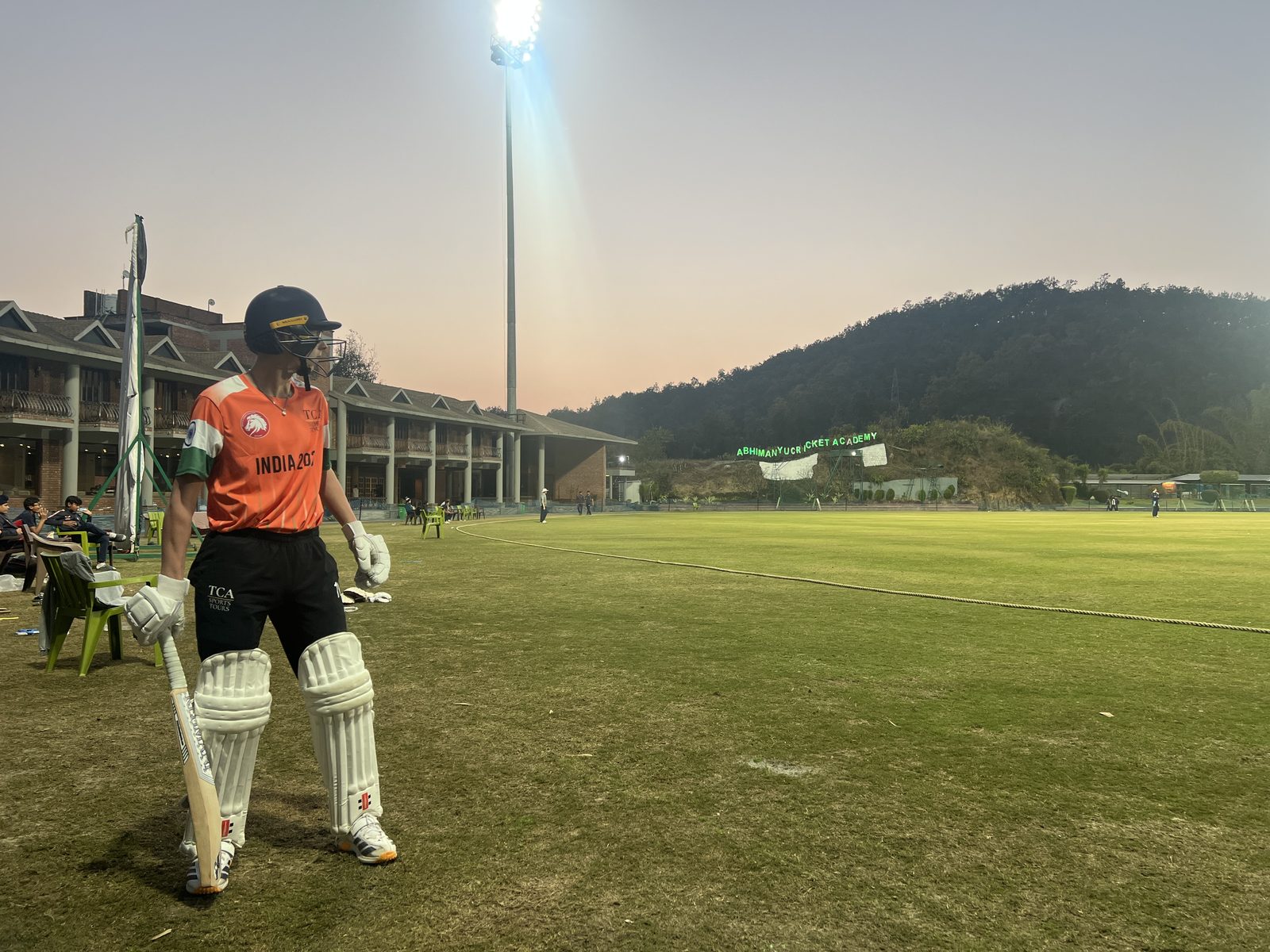 A batter waiting to go in under the floodlights at the Abhimanyu Cricket Academy