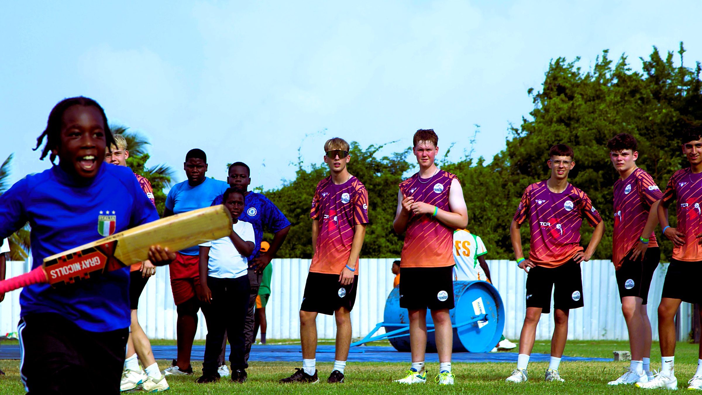A local child with a bat alongside the visiting players